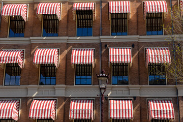 Uniform apartments with lots of windows and red and white striped canopies