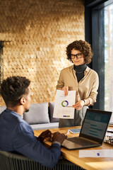 Confident businesswoman pointing at circle diagram on paper document while explaining graphic data...