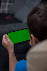 Back view of young europen 6 years old boy who is using chroma key smartphone screen.