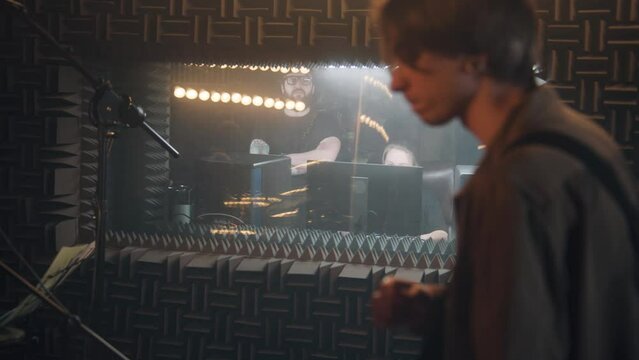 Experienced audio engineer or producer looks at musicians work and edits sound effects in sound recording studio. Musical band plays on instruments and records new song. Concept of music Generative AI