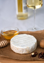 Soft cheese with white mold Camembert, honey, nuts and a glass of wine and a bottle of wine in the background. Close-up. Selective focus.