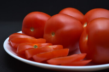 Red tomatoes on a white plate. Chopped tomatoes. Vegetables on a plate.