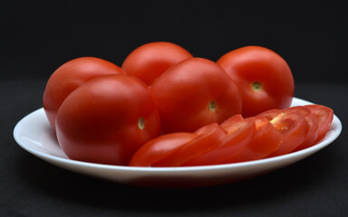 Red tomatoes on a white plate. Chopped tomatoes. Vegetables on a plate.