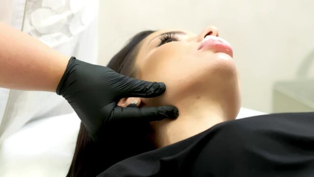 beautician hand's examining beautiful young female face.