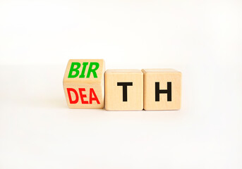 Birth or death symbol. Businessman turns wooden cubes and changes the word Death to Birth. Beautiful white table white background, copy space. Business and birth or death concept.