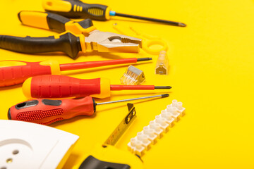 Electrician equipment on yellow background with copy space.Top view.Electrician tool set.Multimeter, tester,screwdrivers,cutters,duct tape,lamps,tape measure and wires.Flet lay. © Avocado_studio