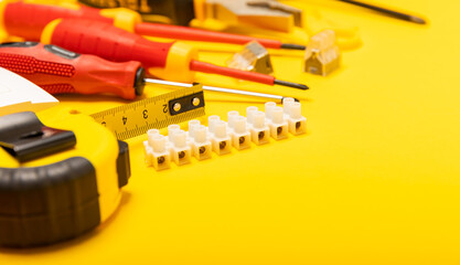Electrician equipment on yellow background with copy space.Top view.Electrician tool set.Multimeter, tester,screwdrivers,cutters,duct tape,lamps,tape measure and wires.Flet lay. © Avocado_studio