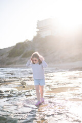 Cute girl waking on wet sandy beach