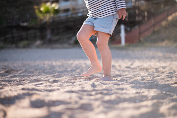 Crop kid walking barefoot on sand