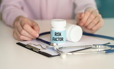 Doctor hands over to the patient a jar with medicine on which the inscription with Risk Factor, close-up of hands on a white background Medical concept.