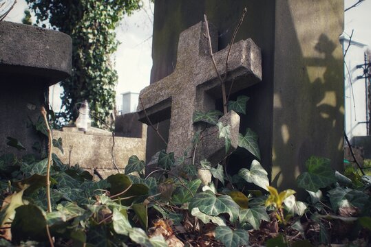 A stone cross leaning against a tombstone in the Orthodox cemetery in Plock