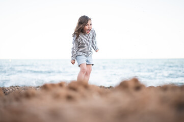 Cheerful girl against splashing sea water on beach