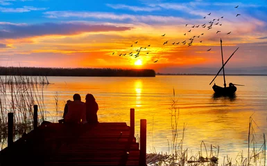 Foto op Plexiglas pareja de enamorados mirando el atardecer en el embarcadero del lago  © kesipun
