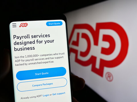 Stuttgart, Germany - 04-26-2023: Person holding smartphone with web page of company Automatic Data Processing Inc. (ADP) on screen with logo. Focus on center of phone display.