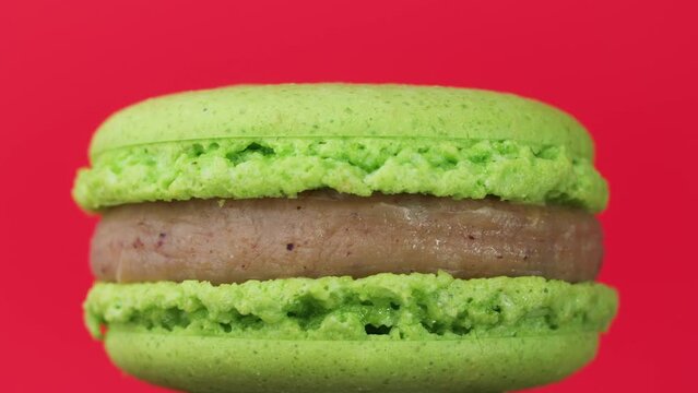 Rotation of a pistachio macaron on a red background.Macro macaron.close up of a traditional french macaron.sweets, pastry and food concept.
