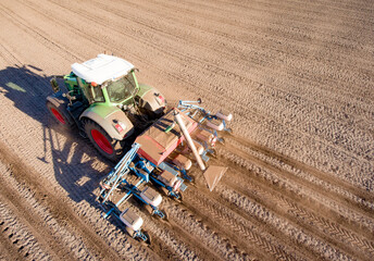 Luftbild - Trecker mit Drillmaschine beim Maislegen auf einem Feld.