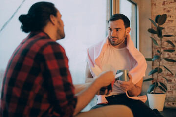 Young men in home clothes are having dinner near the window of the house. A couple of men in love are sitting on the windowsill
