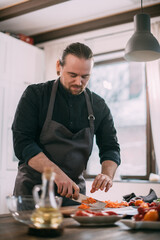 A male cook prepares vegetables at home in the kitchen