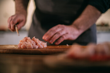 A male chef prepares fresh meat at home in the kitchen..