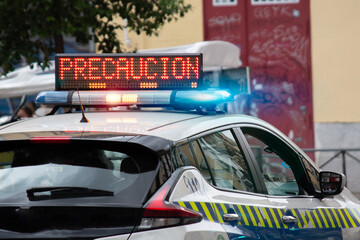 Spanish Police car with light on the roof in which you can read in Spanish CAUTION (PRECAUCION)