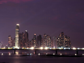 Fototapeta na wymiar Glowing city lights and tall architectural buildings under purple twilight sky