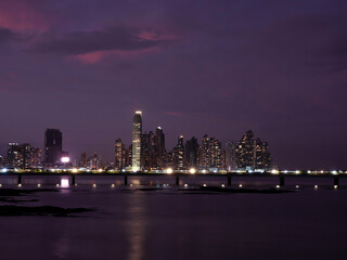 Fototapeta na wymiar Wonderful purple coloured sky above the illuminated modern city district at dusk