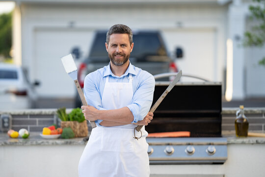 image of chef man at barbecue and grill in apron. chef man at barbecue and grill.