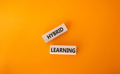 Hybrid learning symbol. Concept word Hybrid learning on wooden blocks. Beautiful orange background. Business and Hybrid learning concept. Copy space