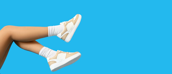 Legs of woman in stylish casual shoes on light blue background with space for text