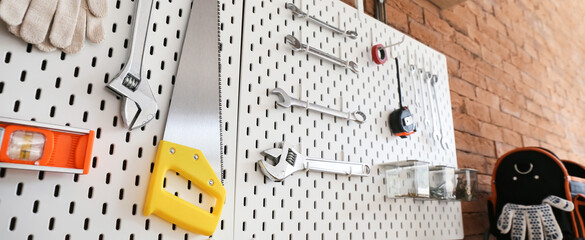 Pegboards with tools hanging on brick wall in workshop