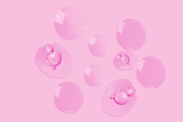 round drops of transparent gel serum on a pink background. gel with bubbles. Water droplets