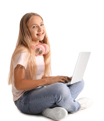 Naklejka premium Little girl with headphones using laptop on white background
