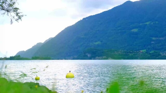 expanse of the blue lake Brienz in Switzerland, the mountains in the background, yellow buoy sways in the water on waves, the concept of sports tourism, weekend hike, active vacation, water sports