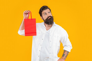 puzzled shopper man at shopping isolated on yellow. shopper man at shopping in studio.