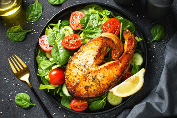 Salmon steak and fresh green salad on black background. Keto diet, healthy food. Mediterranean diet.