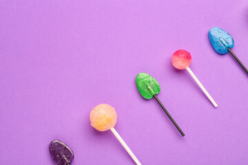 Composition with sweet lollipops on purple background