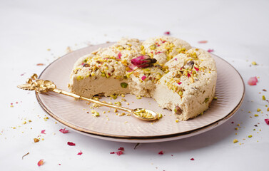 Plate of tasty Tahini halva with pistachios on white background