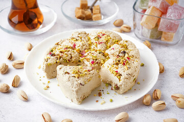 Plate of tasty Tahini halva with pistachios on light background