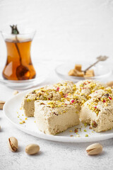Plate of tasty Tahini halva with pistachios on light background