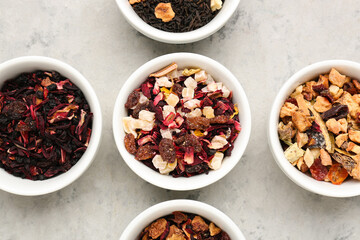 Bowls with different dried fruit tea on grey grunge table