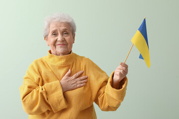 Senior woman with flag of Ukraine on green background