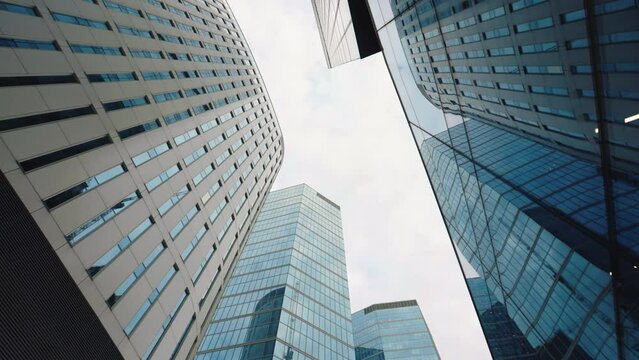 High rise skyscrapers facades low angle dolly effect, financial district looking up modern architecture office buildings, city business downtown, wide shot gimbal moving camera glide, view from below