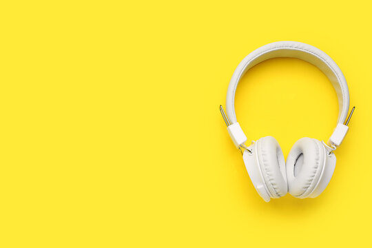 Modern white headphones on yellow background