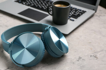 Modern blue headphones with laptop on grey grunge background