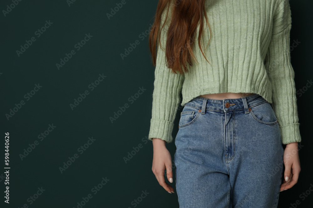 Wall mural Young woman in stylish jeans on green background, closeup