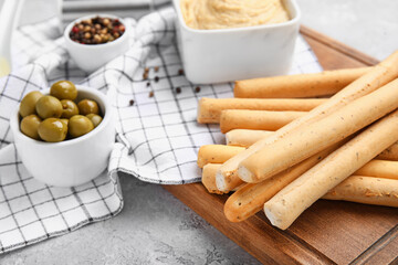 Wooden board with tasty Italian Grissini on table, closeup