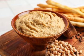 Bowl with tasty hummus on table, closeup