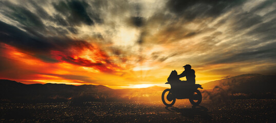 Silhouette of a motorcyclist tackling the Dakar rally at sunset