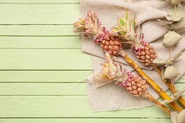 Decorative pineapples with eucalyptus branches on green wooden background