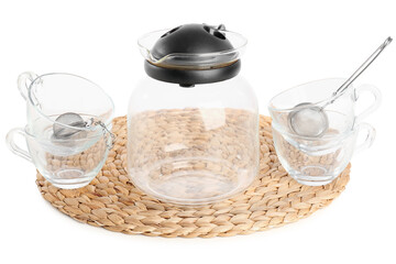 Wicker mat with teapot, glass and infusers isolated on white background